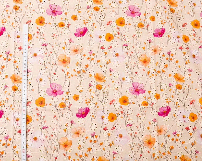 Floral patterned fabric with pink and orange flowers on a beige background, measured with a ruler.