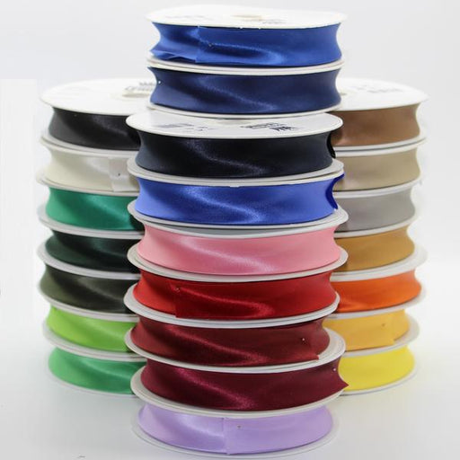 Stack of colorful satin ribbons on spools against a white background