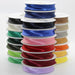 Stack of colorful satin ribbons on spools against a white background