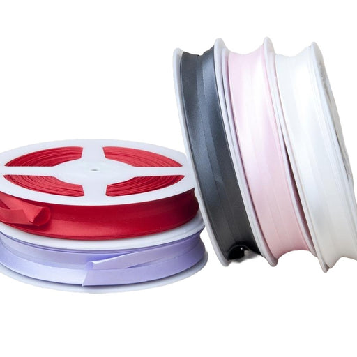 Two spools of ribbon, one red and one white, on a white background.